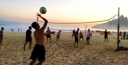 Imagem de pessoas jogando vôlei na praia.